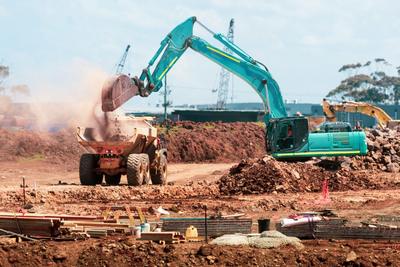 Escavadora a descarregar terra para um camião numa obra