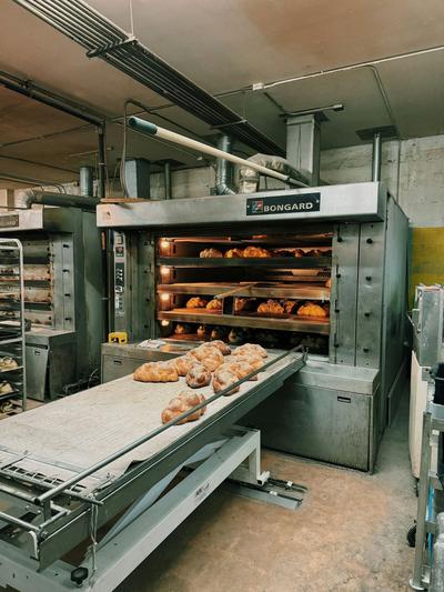 Forno industrial de padaria com pão a sair num tapete