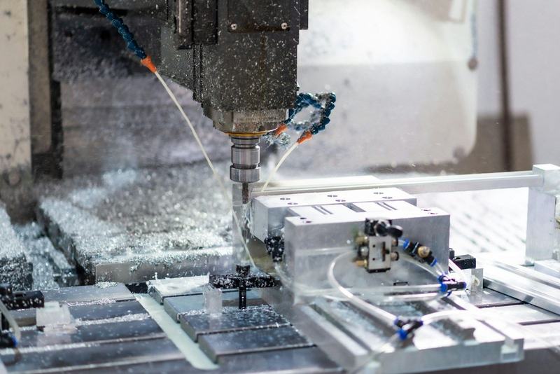 Fresa de um centro de maquinação CNC a cortar uma peça metálica, com apara e refrigerante