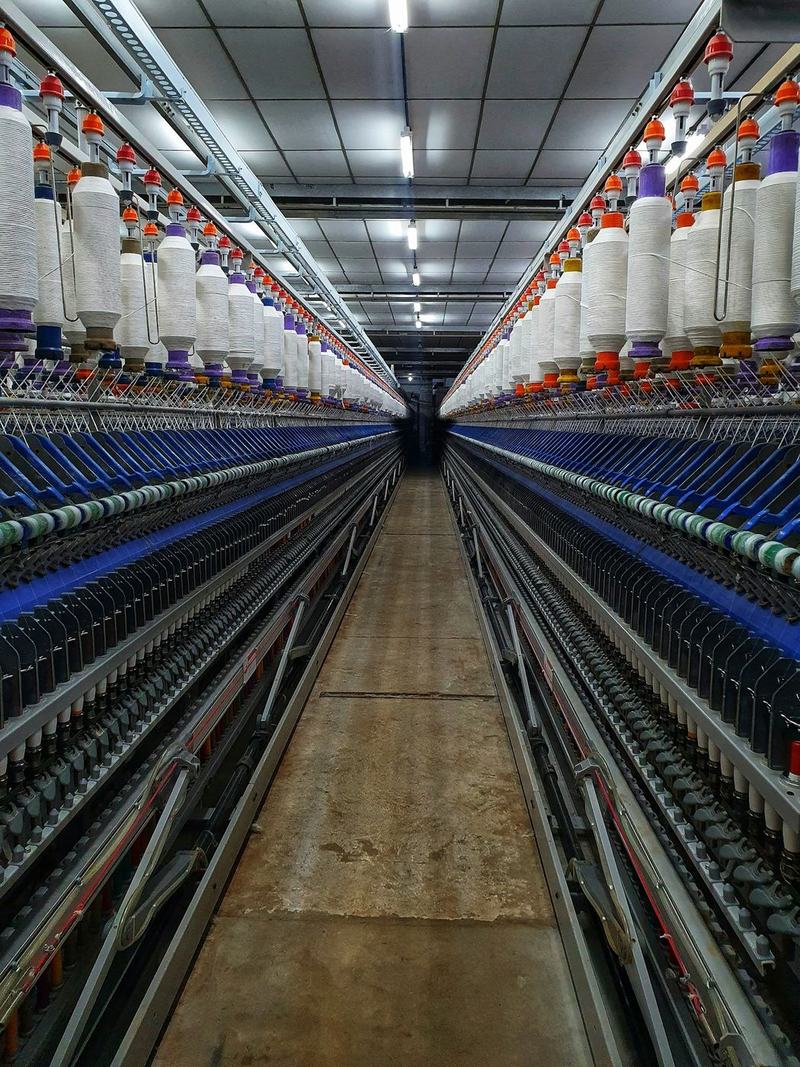 Corredor entre duas filas de contínuos de fiar numa fábrica têxtil
