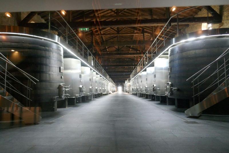 Adega com filas de cubas de inox de fermentação, ao longo de um corredor