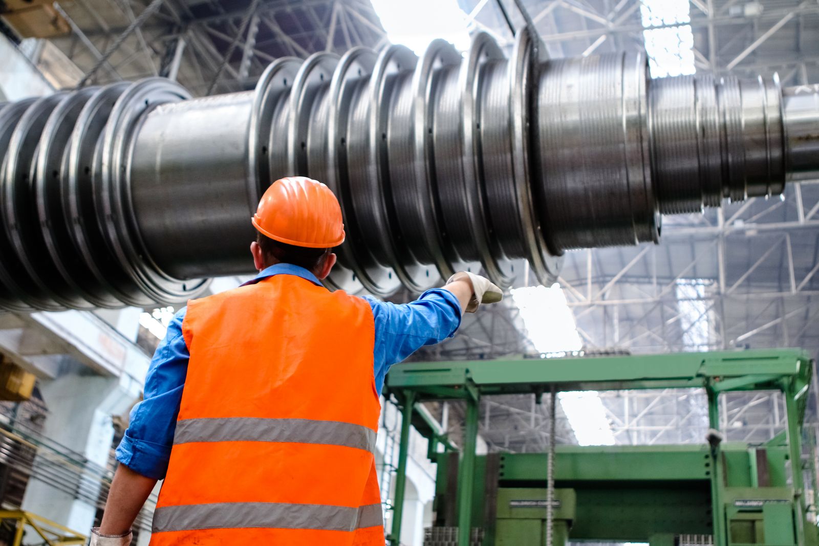Técnico a inspecionar o rotor de uma grande turbina numa nave industrial