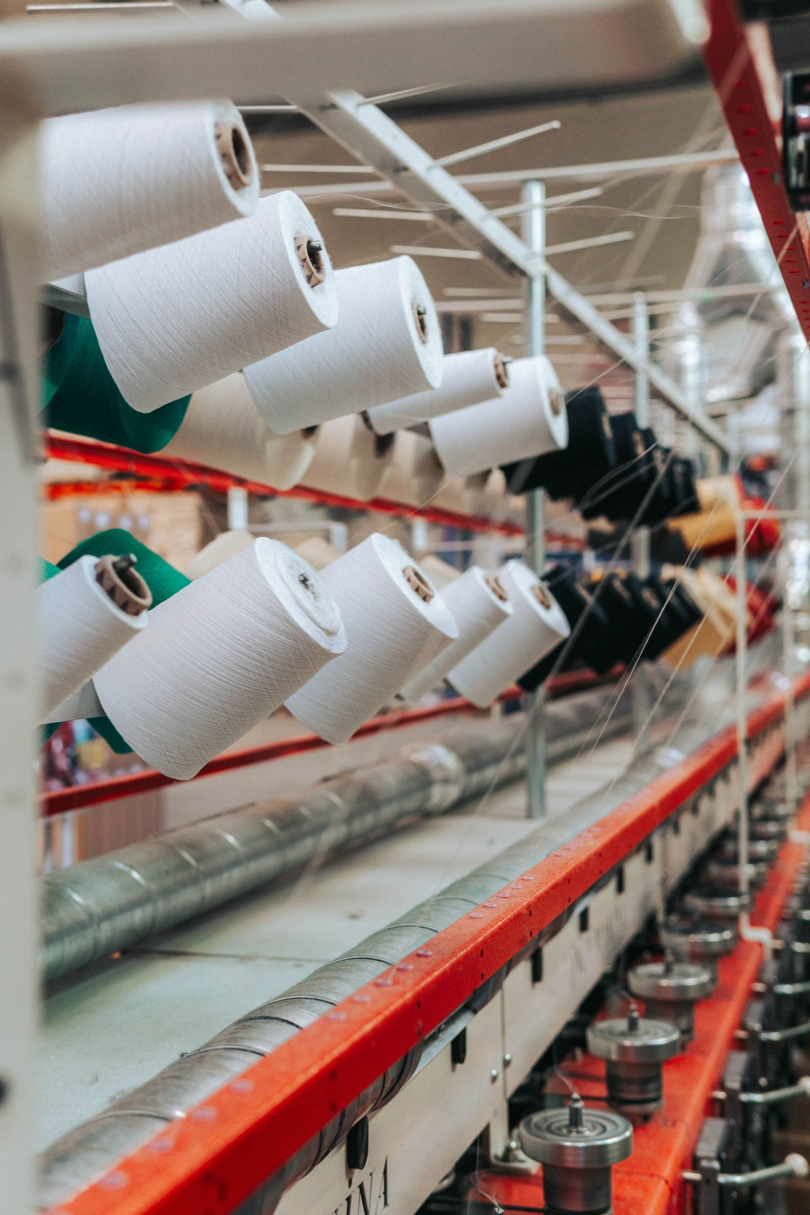 Cones de fio brancos numa máquina de fiação têxtil