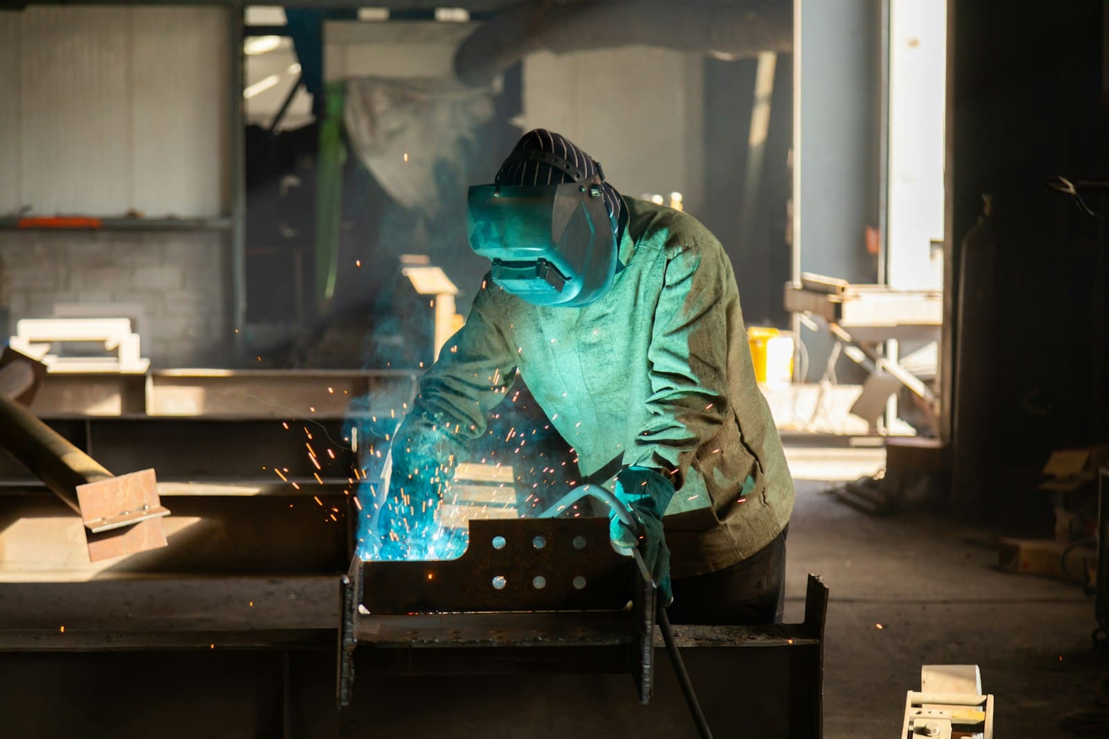 Soldador a trabalhar uma peça de aço numa oficina metalomecânica